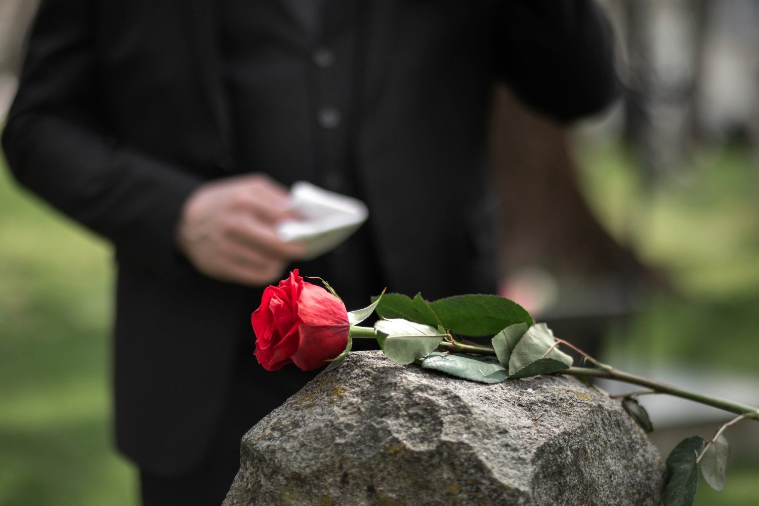 Man paying respect to a tombstone at the cemetery