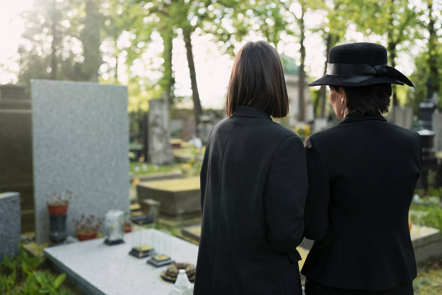 Mourning mother and daughter at a grave in the cemetery